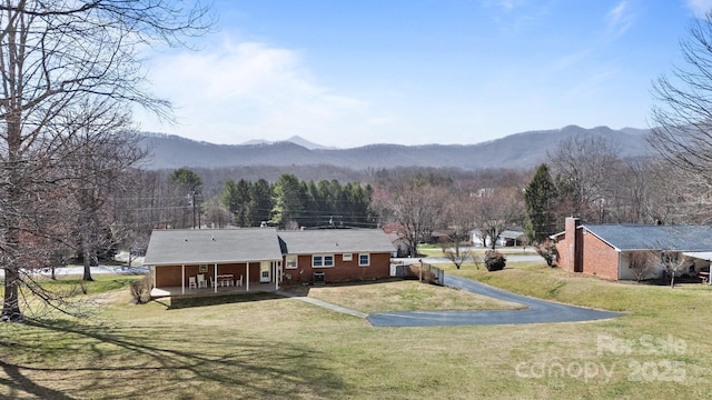 exterior space featuring covered porch, a mountain view, and a yard