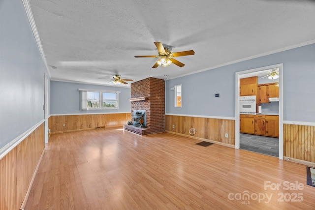 unfurnished living room with wooden walls, a textured ceiling, and wainscoting