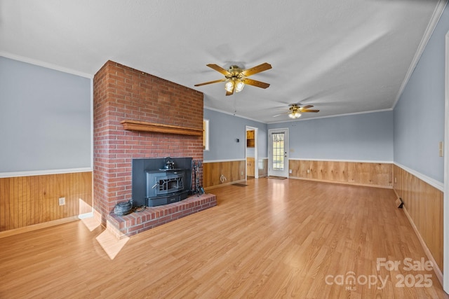 unfurnished living room with a wood stove, a wainscoted wall, and wood walls