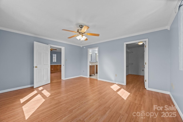 empty room with light wood finished floors, baseboards, and crown molding