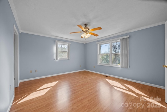 spare room featuring crown molding, wood finished floors, a ceiling fan, and baseboards