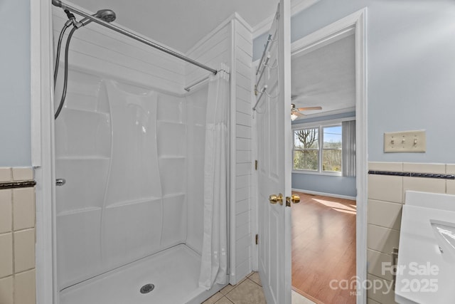 full bathroom with tile walls, ceiling fan, a shower stall, and tile patterned floors