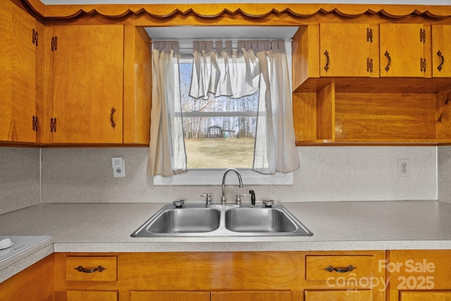 kitchen featuring brown cabinetry, light countertops, and a sink