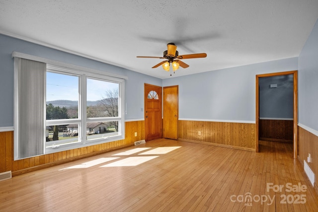 empty room featuring a wainscoted wall, hardwood / wood-style floors, and visible vents