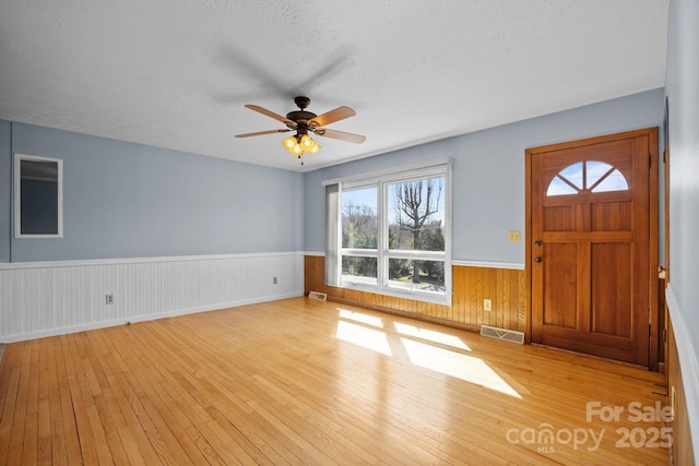 entryway with hardwood / wood-style flooring, visible vents, a textured ceiling, and wainscoting