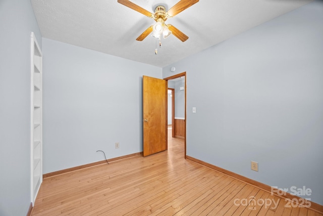 empty room featuring light wood-type flooring, a textured ceiling, baseboards, and a ceiling fan