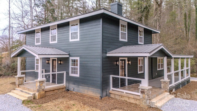 view of front of house with metal roof, a chimney, and a porch