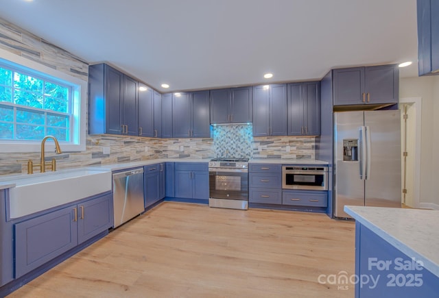 kitchen with recessed lighting, decorative backsplash, appliances with stainless steel finishes, light wood-style floors, and a sink