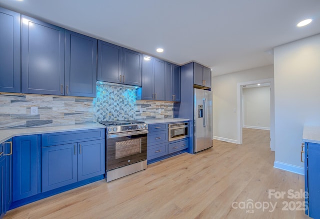 kitchen with blue cabinetry, stainless steel appliances, decorative backsplash, and light countertops