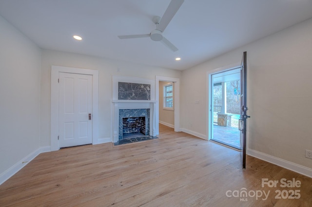 unfurnished living room with a premium fireplace, recessed lighting, wood finished floors, and baseboards