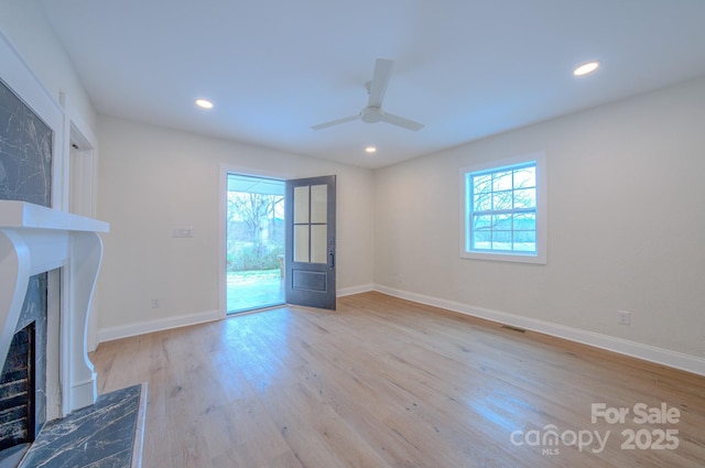 unfurnished living room featuring baseboards, visible vents, light wood-style floors, a fireplace, and recessed lighting