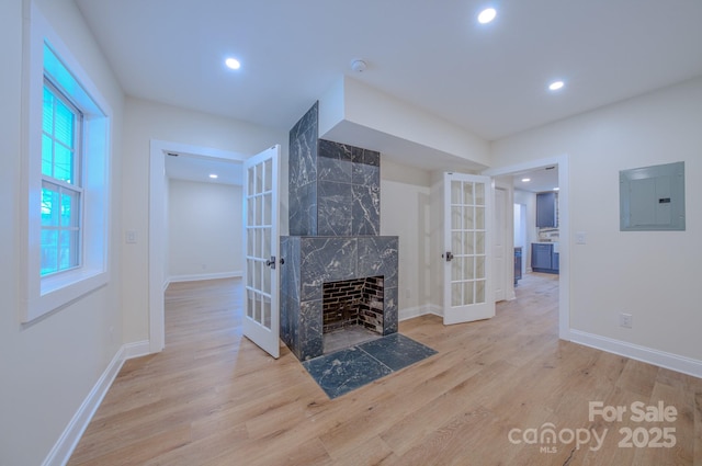 unfurnished living room with electric panel, wood finished floors, french doors, a fireplace, and recessed lighting