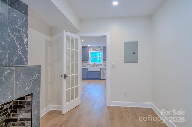 hall featuring recessed lighting, a sink, baseboards, light wood-type flooring, and electric panel