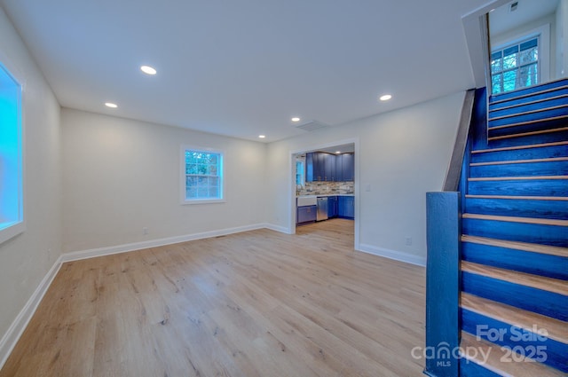 unfurnished living room featuring light wood finished floors, stairs, baseboards, and recessed lighting