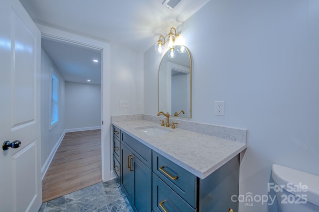 half bath featuring toilet, baseboards, visible vents, and vanity