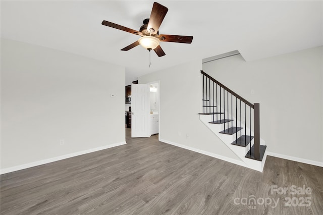 interior space with a ceiling fan, stairs, baseboards, and wood finished floors