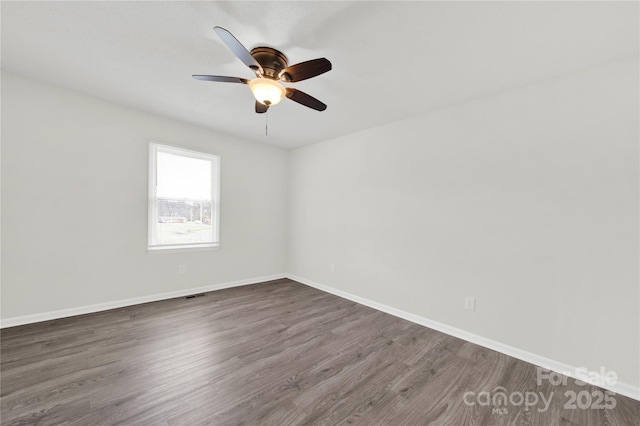 spare room featuring dark wood-style floors, baseboards, visible vents, and a ceiling fan