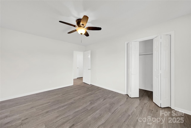 unfurnished bedroom featuring ceiling fan, a closet, baseboards, and wood finished floors