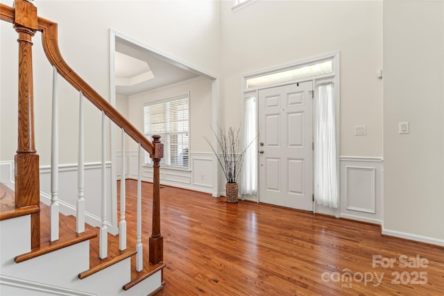 entryway with stairs, wainscoting, wood finished floors, and a decorative wall