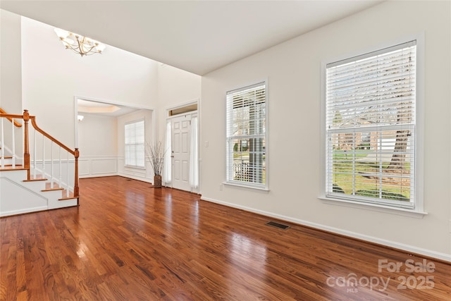 foyer entrance with a wealth of natural light, visible vents, stairway, and wood finished floors