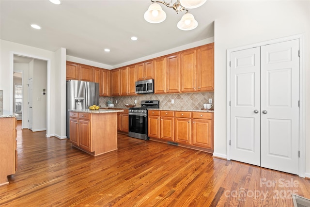 kitchen featuring stainless steel appliances, backsplash, and wood finished floors