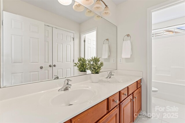 bathroom with double vanity, tile patterned flooring, toilet, and a sink