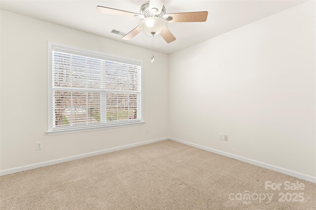 carpeted spare room featuring baseboards, visible vents, and a ceiling fan