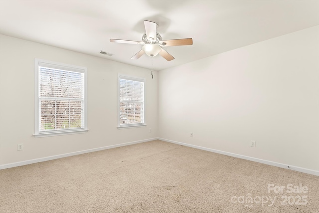 carpeted spare room featuring baseboards, visible vents, and ceiling fan