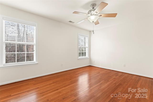 empty room with visible vents, ceiling fan, baseboards, and hardwood / wood-style flooring