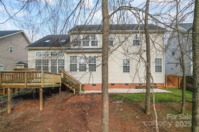 rear view of property with a shingled roof, crawl space, fence, a deck, and a patio area