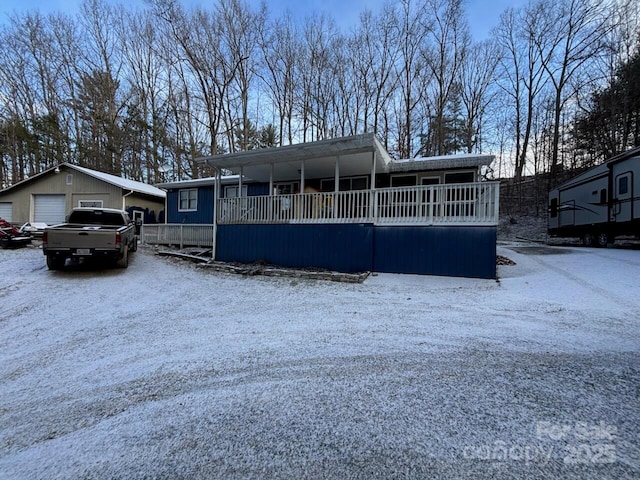 manufactured / mobile home with a porch, a detached garage, and an outdoor structure