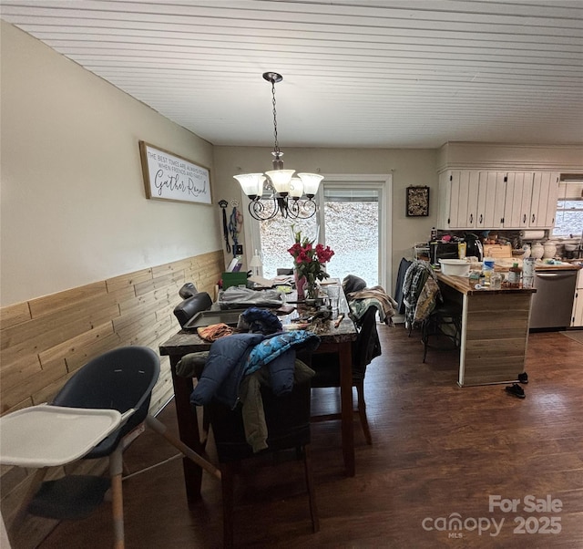 dining space with dark wood-style flooring and an inviting chandelier