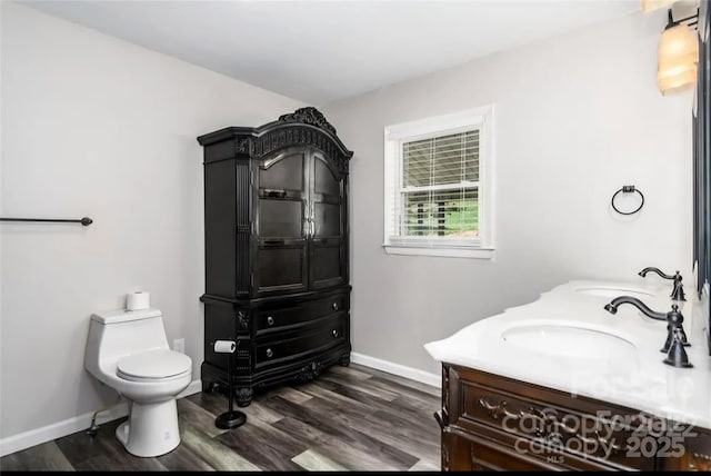 bathroom featuring baseboards, vanity, toilet, and wood finished floors