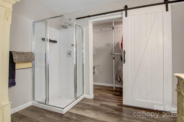 full bathroom with a stall shower, baseboards, and wood finished floors