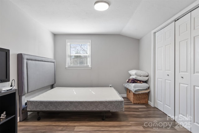 bedroom with vaulted ceiling, a closet, dark wood finished floors, and baseboards