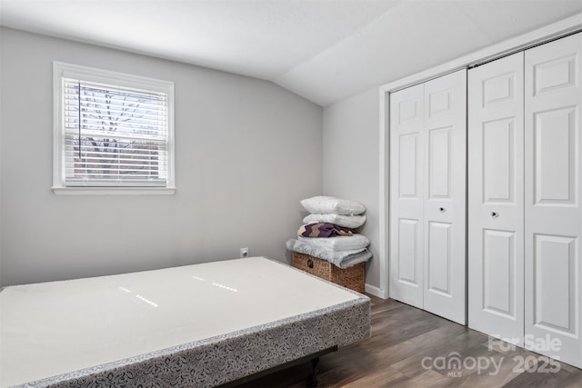 bedroom with dark wood-style floors, vaulted ceiling, and a closet