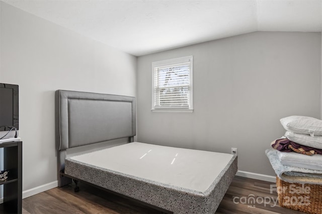 bedroom with lofted ceiling, dark wood-style floors, and baseboards