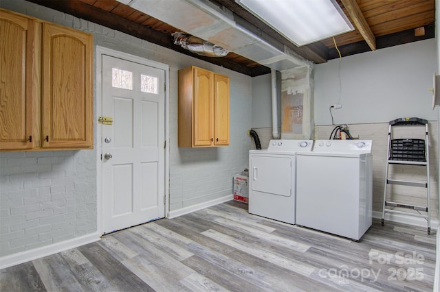 laundry room with cabinet space, independent washer and dryer, light wood-style flooring, and brick wall