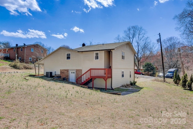 back of property with stairs, a yard, and central air condition unit