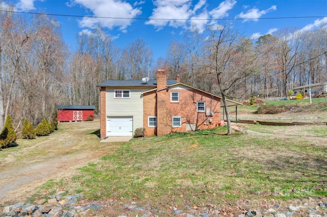 exterior space featuring brick siding, a yard, a chimney, a garage, and driveway