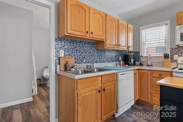 kitchen with white appliances, tasteful backsplash, dark wood-type flooring, light countertops, and a sink