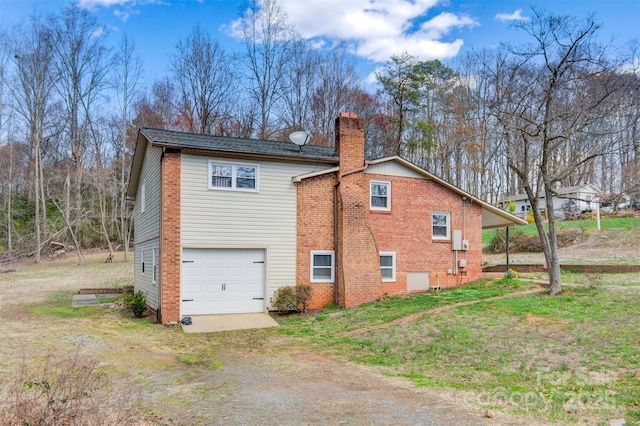 view of side of home featuring a garage, a yard, driveway, and a chimney