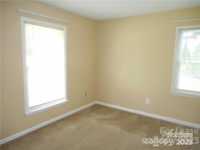 carpeted spare room featuring baseboards