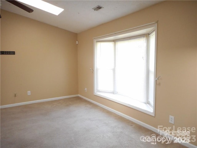 carpeted spare room with a healthy amount of sunlight, visible vents, and baseboards