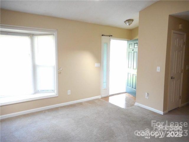 unfurnished room featuring carpet and baseboards