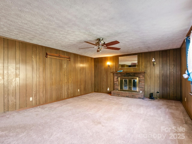 unfurnished living room featuring a textured ceiling, wood walls, a fireplace, and carpet flooring