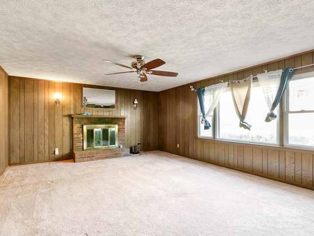 unfurnished living room with carpet, a brick fireplace, plenty of natural light, and wood walls