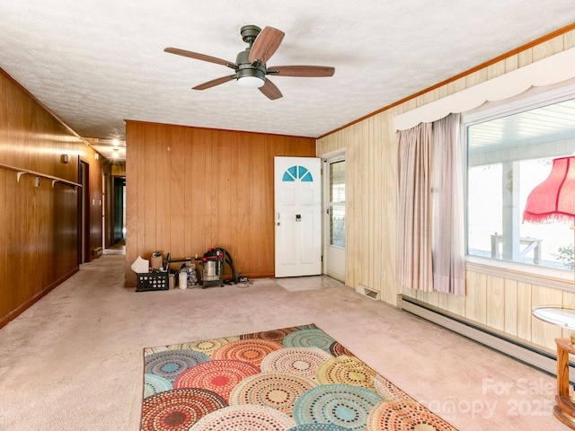 foyer entrance featuring a baseboard heating unit, carpet floors, a textured ceiling, and wooden walls