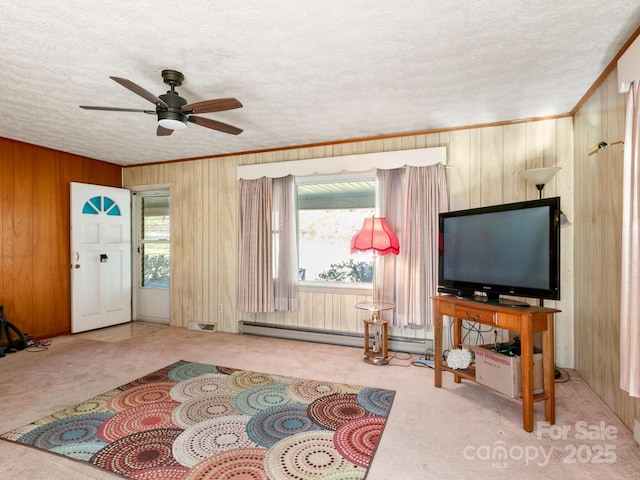 living room featuring a textured ceiling, a baseboard heating unit, carpet floors, wood walls, and ornamental molding