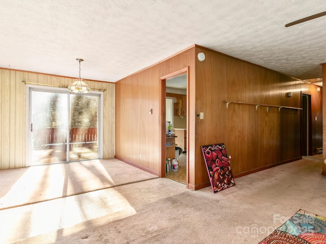 interior space featuring carpet floors, baseboards, a textured ceiling, and wooden walls